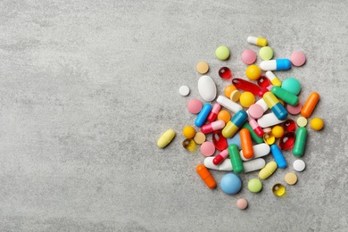 Photo of Heap of different pills on grey background, top view. Space for text