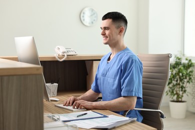 Photo of Smiling medical assistant working with computer at hospital reception