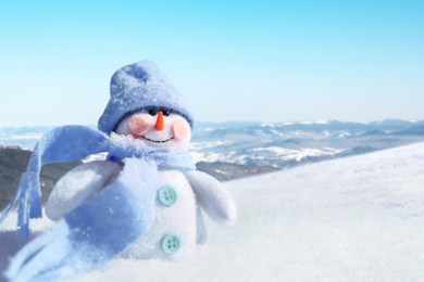 Image of Cute small decorative snowman outdoors on sunny day, space for text