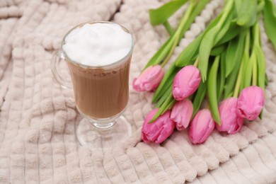 Photo of Glass of delicious cocoa and pink tulips on light blanket