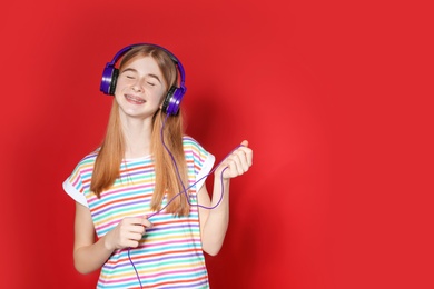 Photo of Teenage girl enjoying music in headphones on color background. Space for text