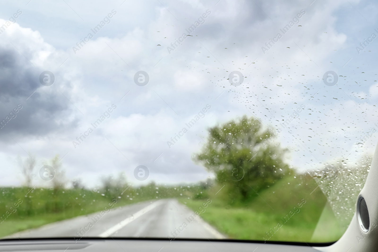 Photo of Blurred view of suburban road through wet car window. Rainy weather