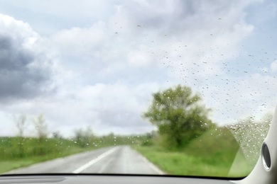 Blurred view of suburban road through wet car window. Rainy weather