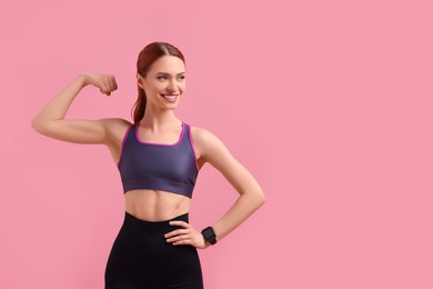 Photo of Young woman in sportswear showing muscles on pink background, space for text