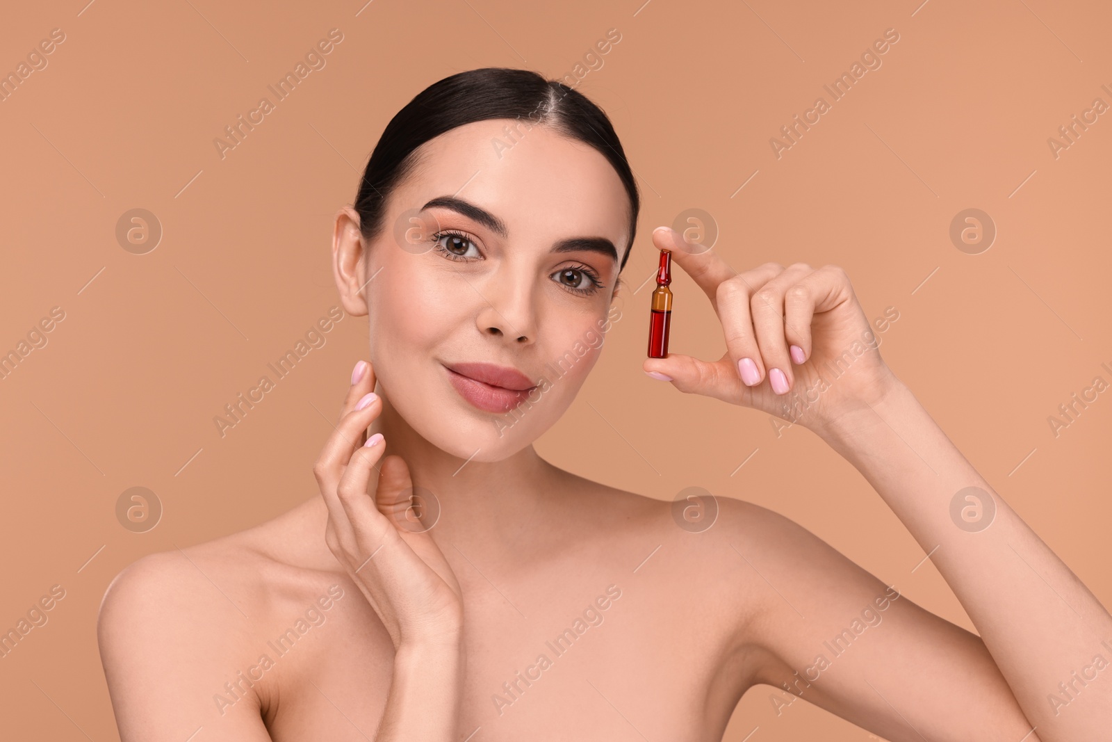 Photo of Beautiful young woman holding skincare ampoule on beige background