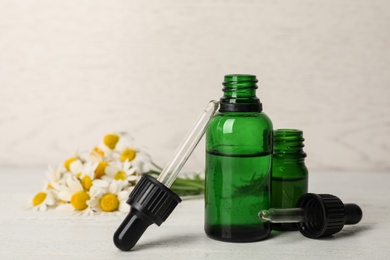 Photo of Composition with bottles of chamomile essential oil on table. Space for text