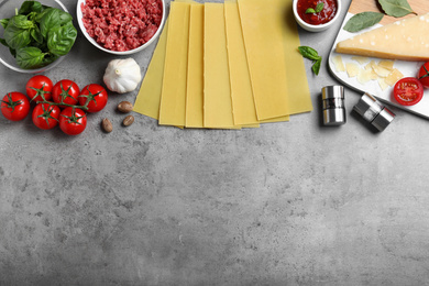 Photo of Fresh lasagna ingredients on grey table, flat lay. Space for text
