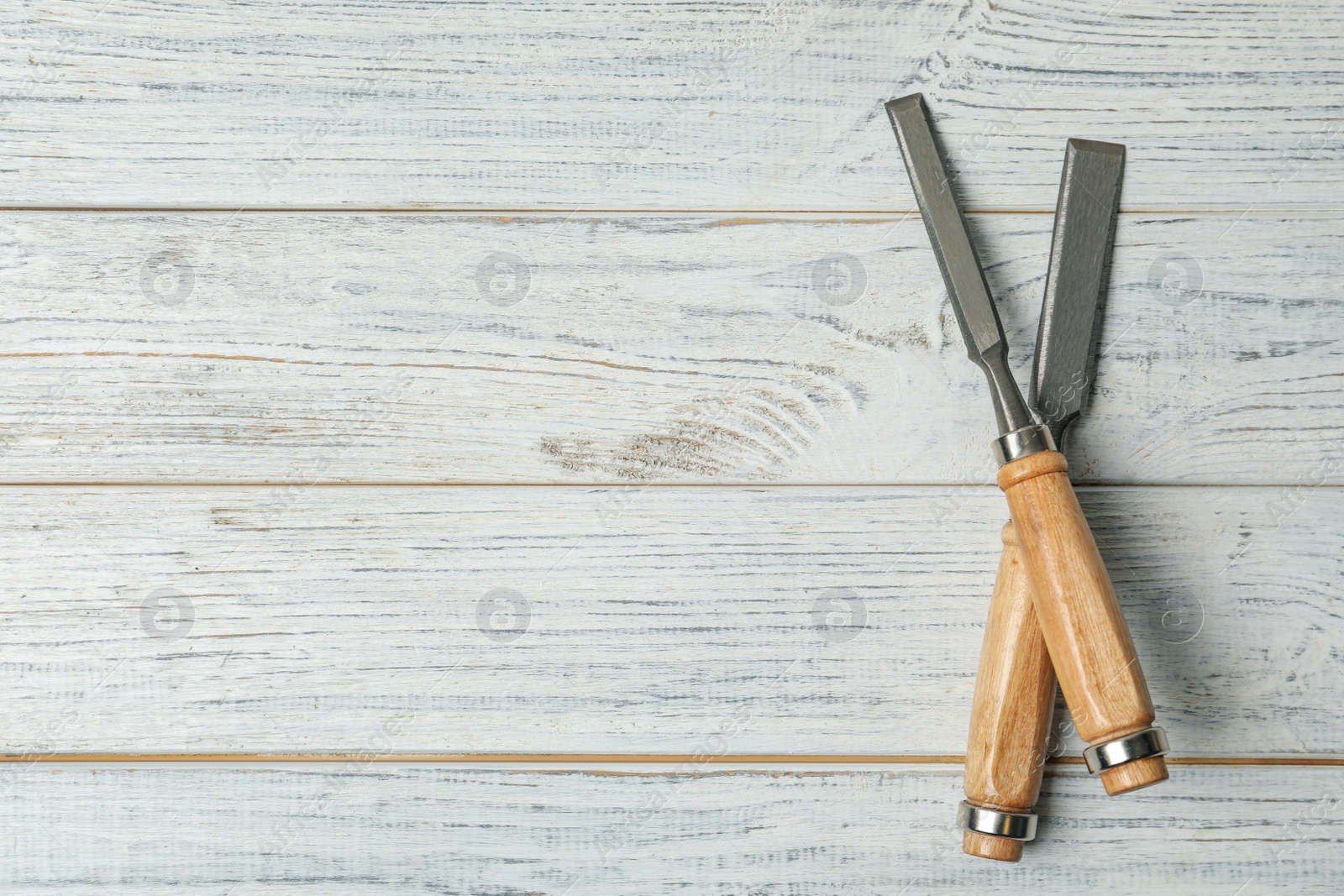 Photo of Modern chisels on white wooden background, flat lay with space for text. Carpenter's tools