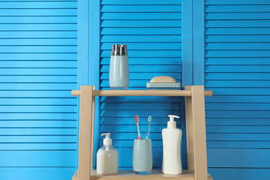 Photo of Wooden shelving unit with toiletries near blue folding screen. Bathroom interior element