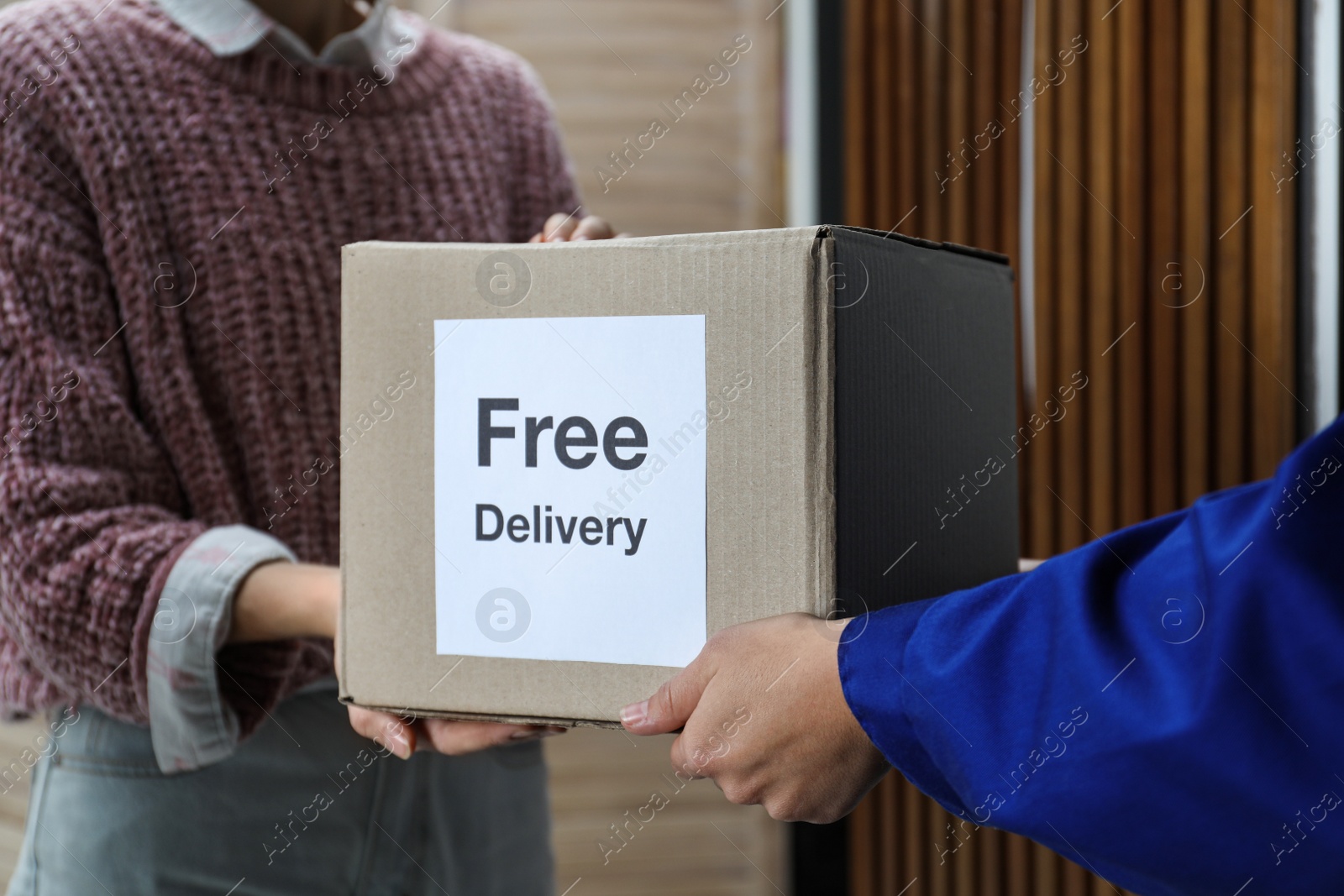 Photo of Woman receiving parcel with sticker Free Delivery from courier indoors, closeup