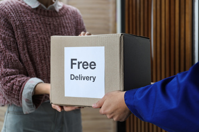 Woman receiving parcel with sticker Free Delivery from courier indoors, closeup