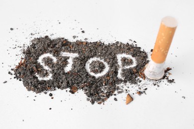 Word Stop made of cigarette ash and stub on white background, closeup. Quitting smoking concept
