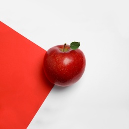 Ripe juicy red apple with leaf on color background, top view