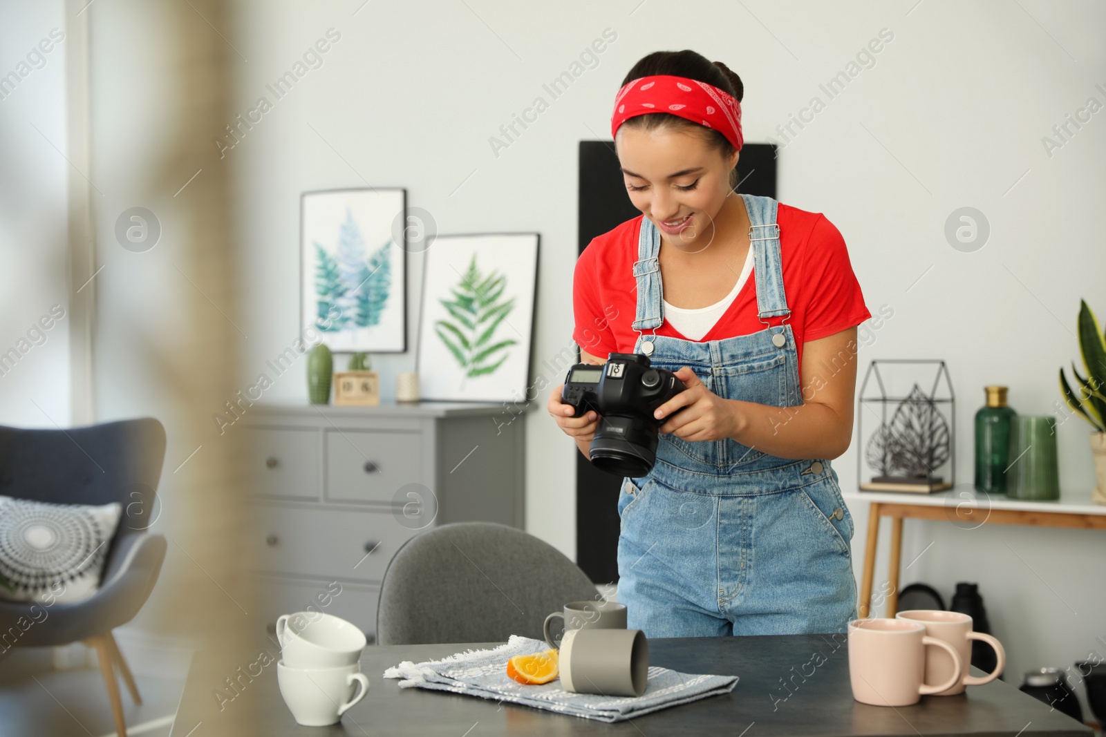 Photo of Young photographer taking picture of cups at table indoors