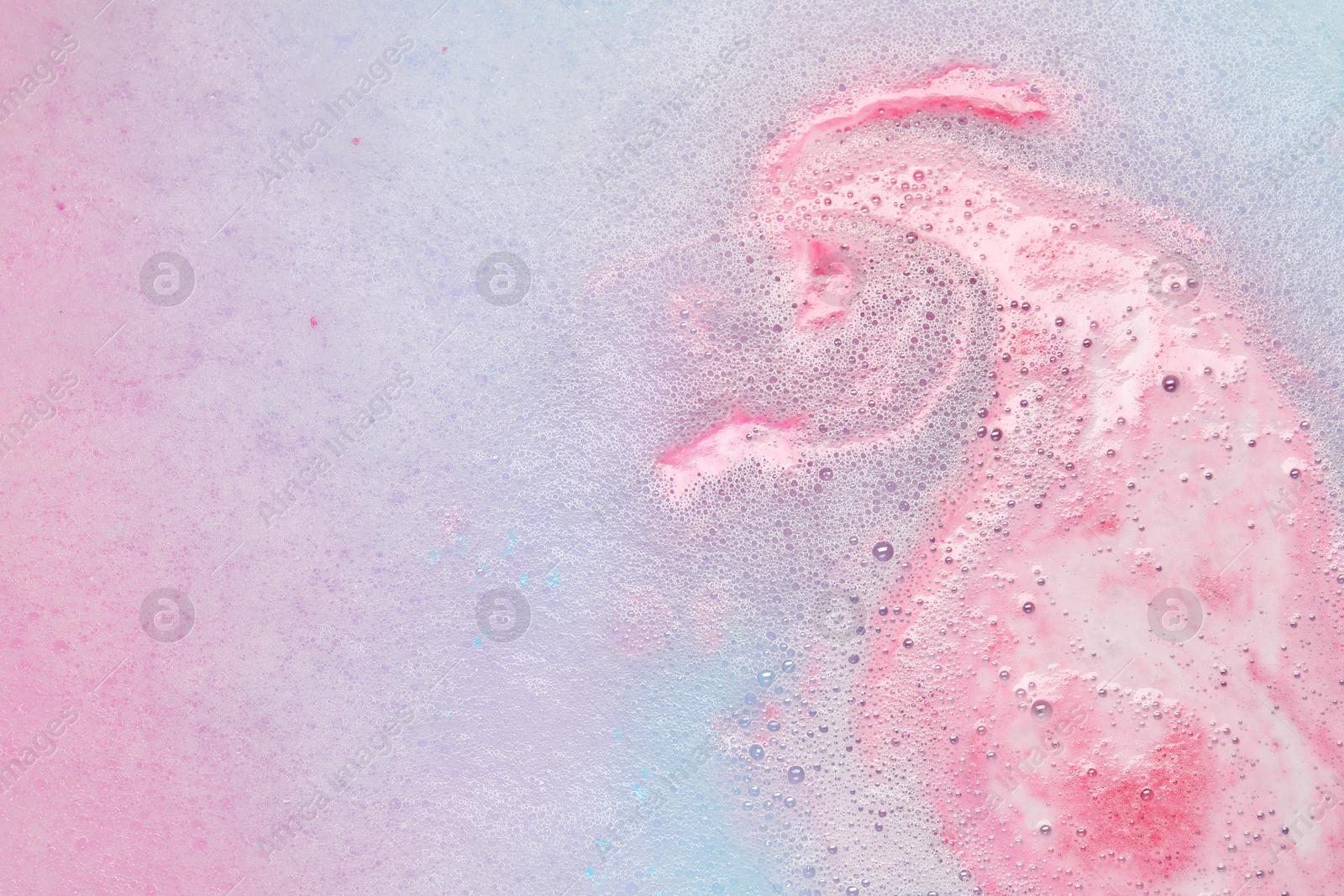 Photo of Colorful foam after dissolving bath bomb in water, closeup