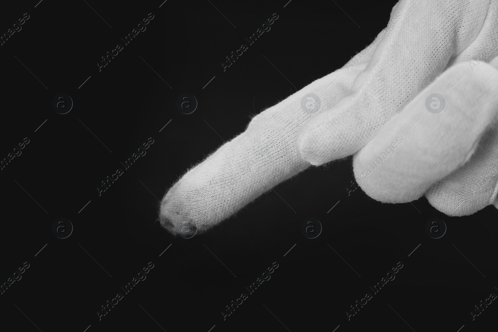 Photo of Person in white glove checking cleanliness of black background, closeup