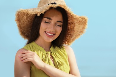 Beautiful young woman wearing straw hat on blurred background. Stylish headdress