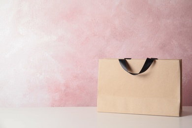 Photo of Paper shopping bag on table against color background. Mock up for design