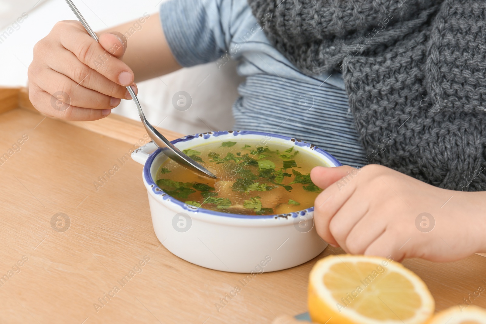 Photo of Sick little boy eating broth to cure cold, closeup