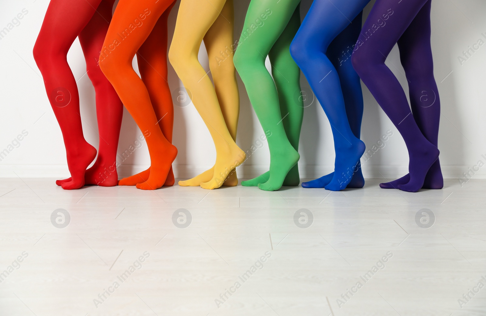 Photo of Women wearing colorful tights near white wall, closeup