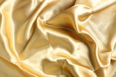 Golden shiny fabric as background, top view