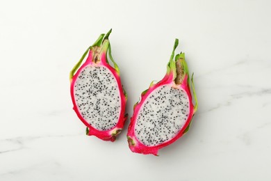Photo of Halves of delicious dragon fruit (pitahaya) on white marble table, flat lay