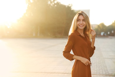 Beautiful young woman in stylish red dress on city street