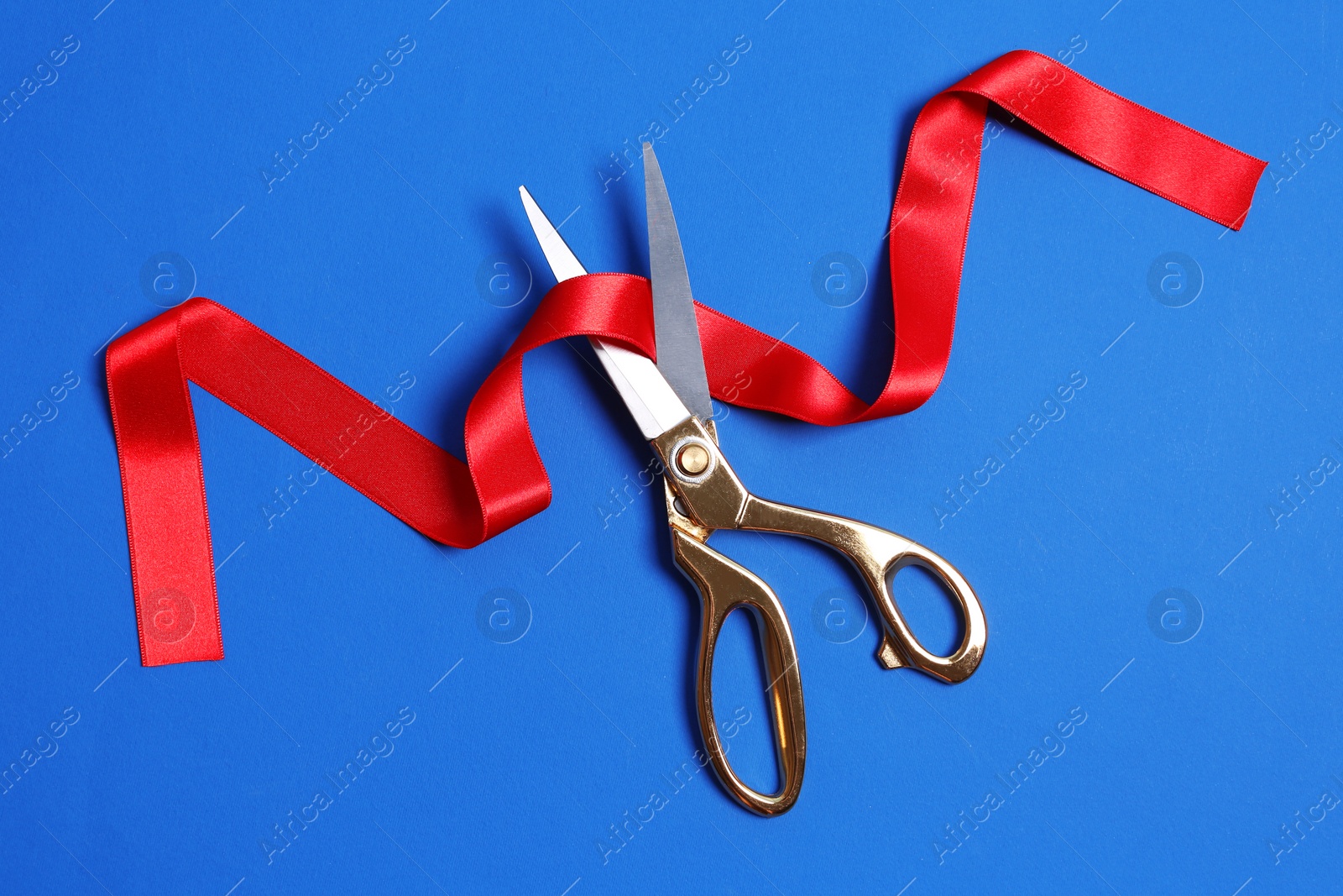 Photo of Ribbon and scissors on color background, top view. Ceremonial red tape cutting