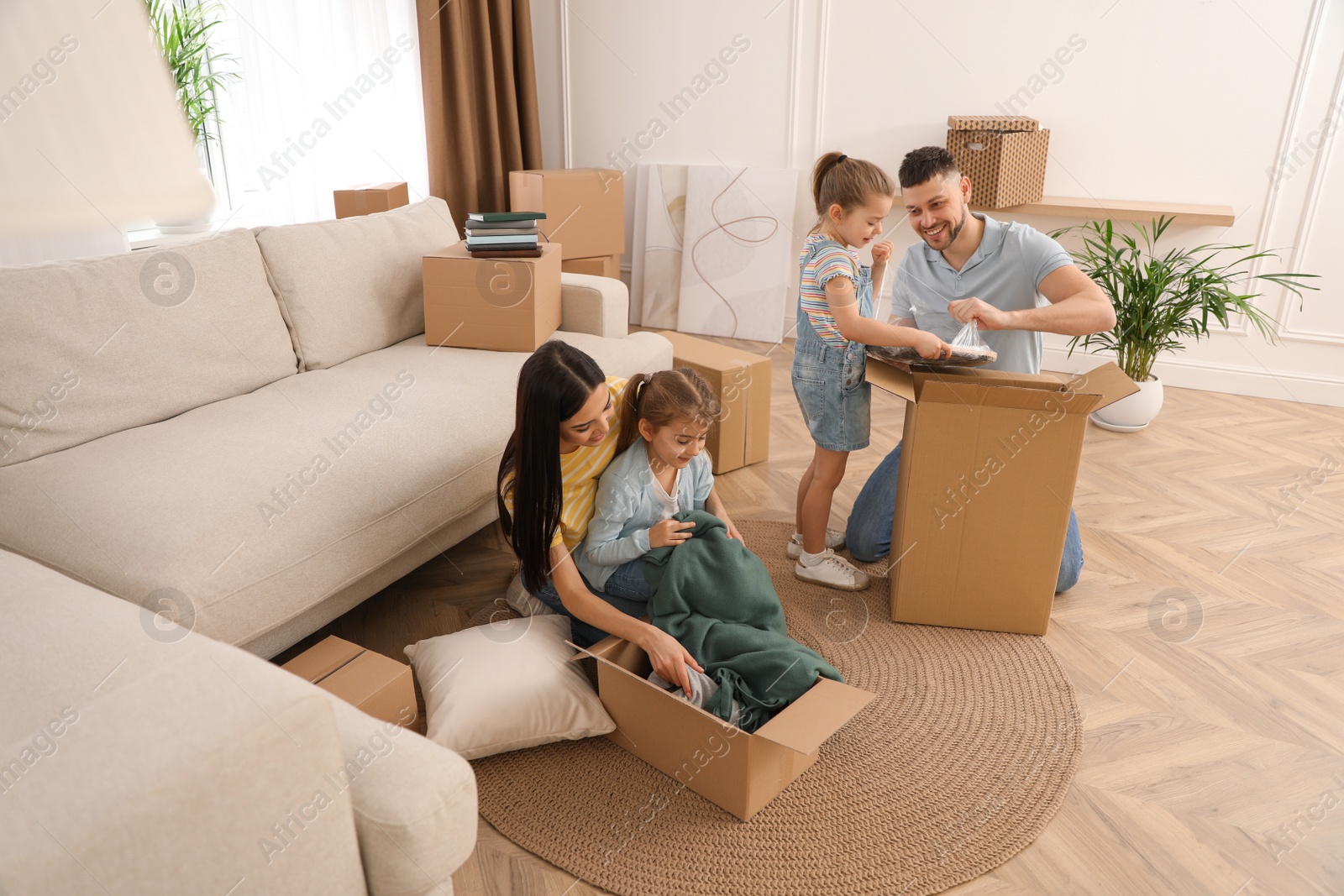 Photo of Happy family unpacking moving boxes at their new house