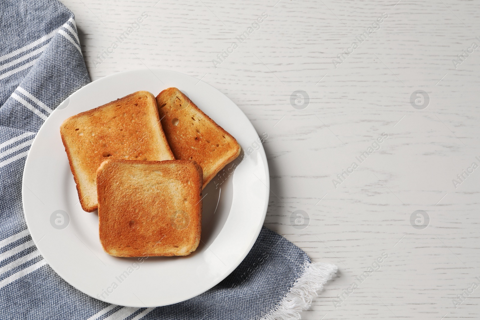 Photo of Plate with slices of delicious toasted bread on white wooden table, top view. Space for text