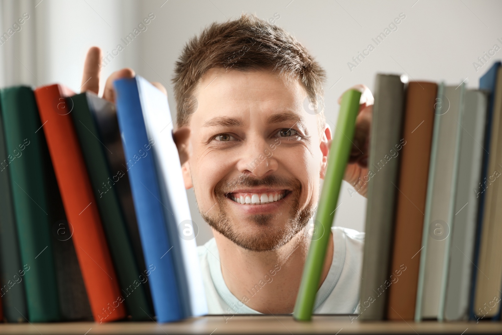 Photo of Man searching for book on shelf in library