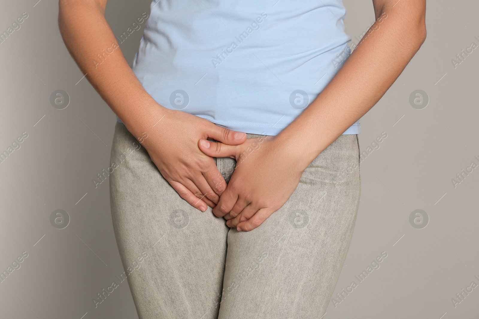 Photo of Woman suffering from genital herpes on light grey background, closeup