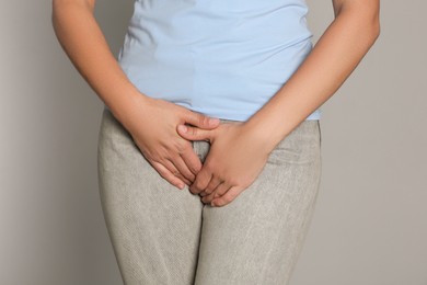 Woman suffering from genital herpes on light grey background, closeup