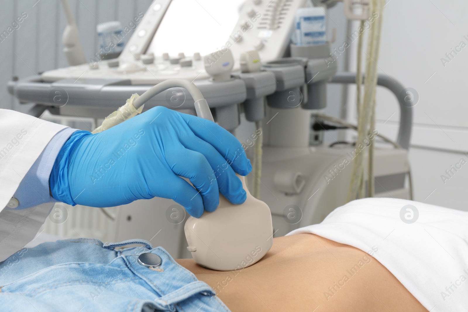 Photo of Doctor conducting ultrasound examination of patient's abdomen in clinic, closeup