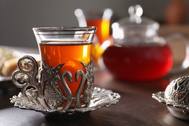 Glass of traditional Turkish tea in vintage holder on wooden table, closeup. Space for text