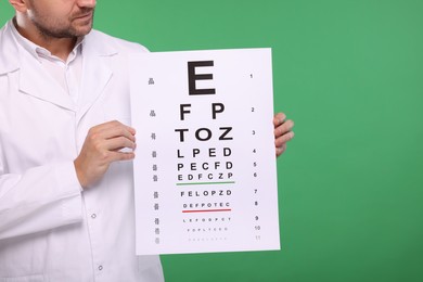 Photo of Ophthalmologist with vision test chart on green background, closeup. Space for text