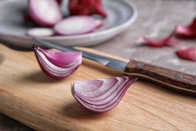 Photo of Wooden board with sliced ripe red onion, closeup