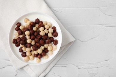 Photo of Breakfast cereal. Tasty corn balls with milk in bowl on white textured table, top view. Space for text