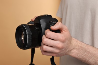 Photographer holding camera on beige background, closeup