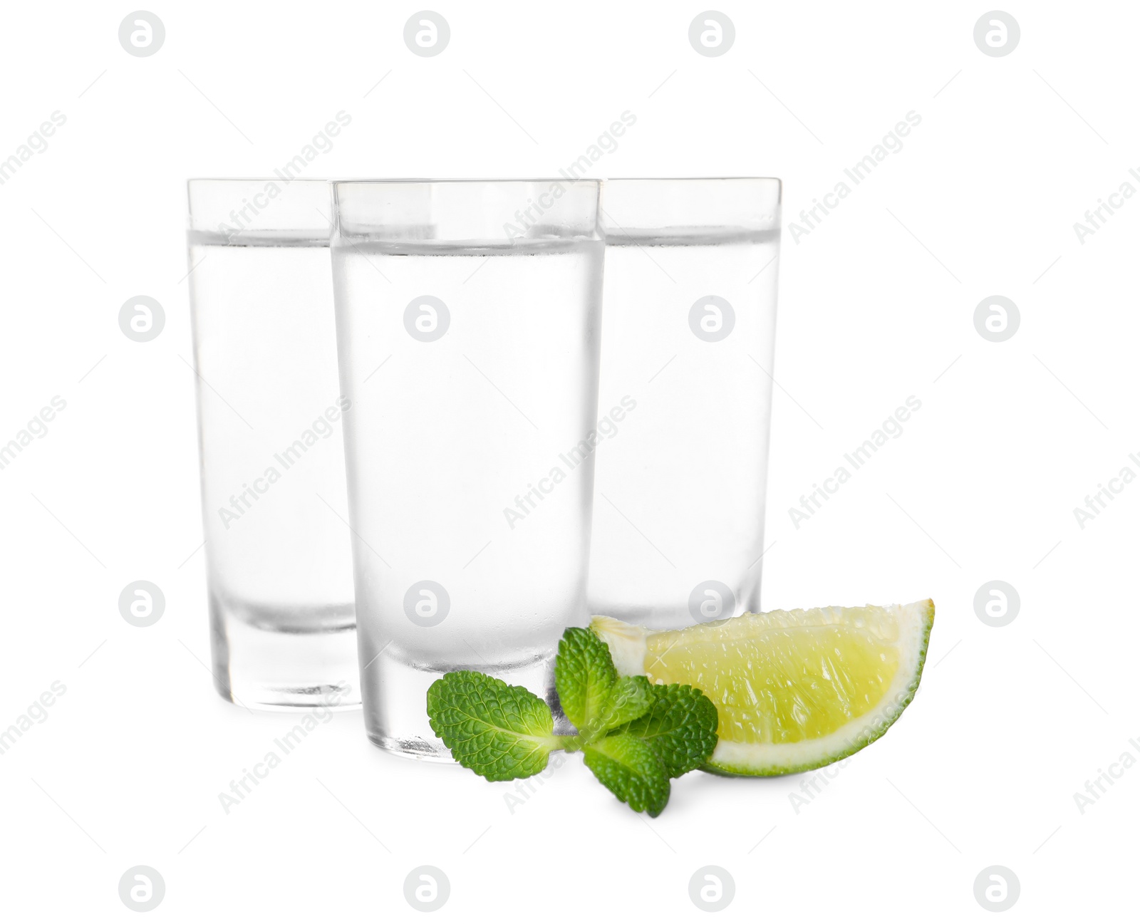 Photo of Shot glasses of vodka with lime and mint on white background