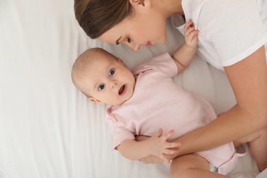 Portrait of mother with her cute baby lying on bed, top view