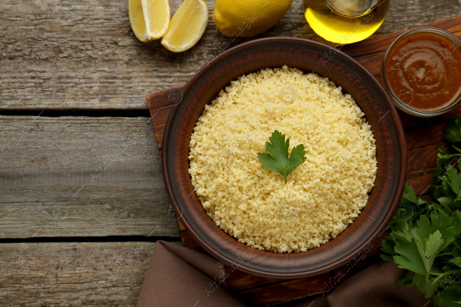 Photo of Tasty couscous and ingredients on wooden table, flat lay. Space for text