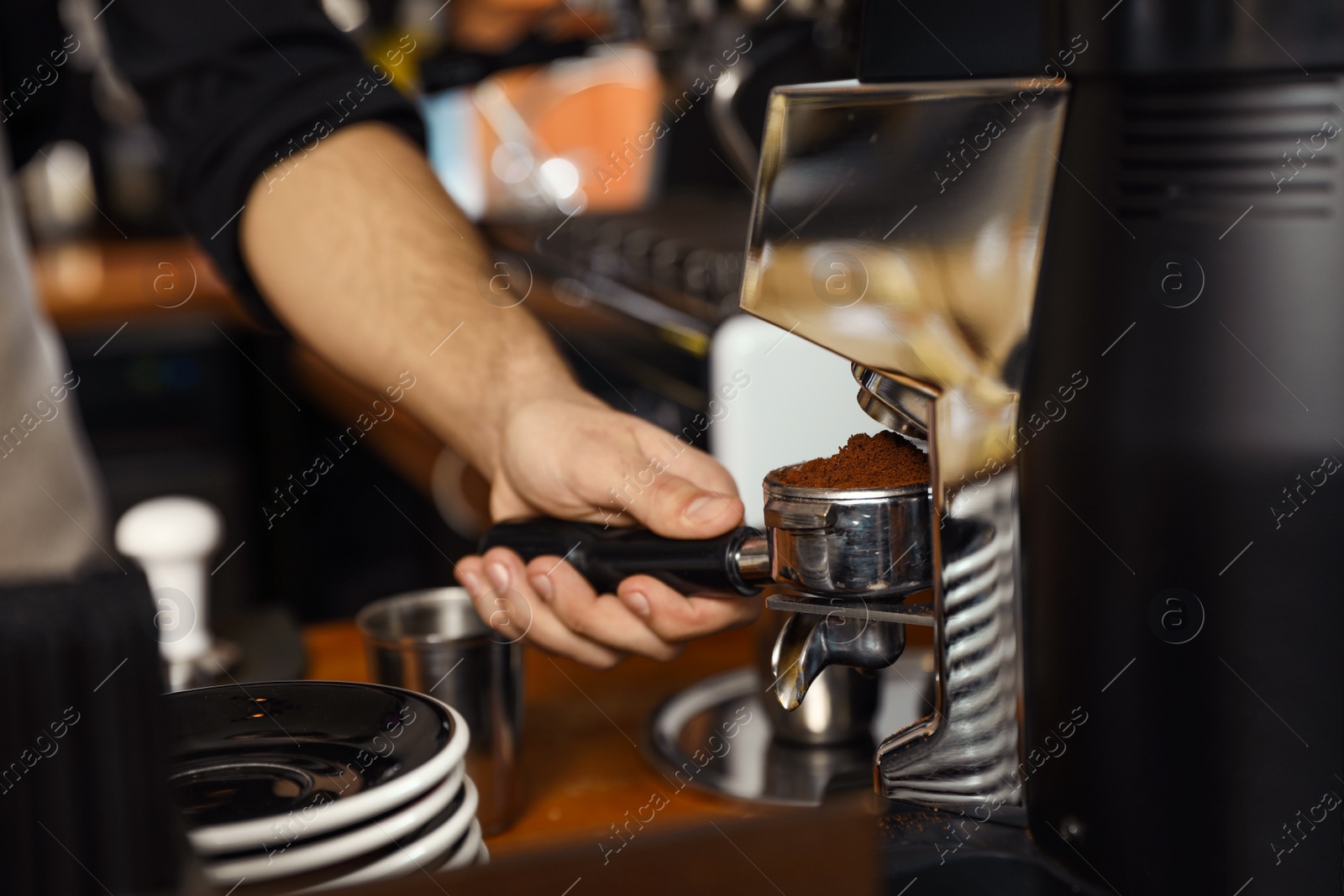 Photo of Barista pouring milled coffee from grinding machine into portafilter, closeup