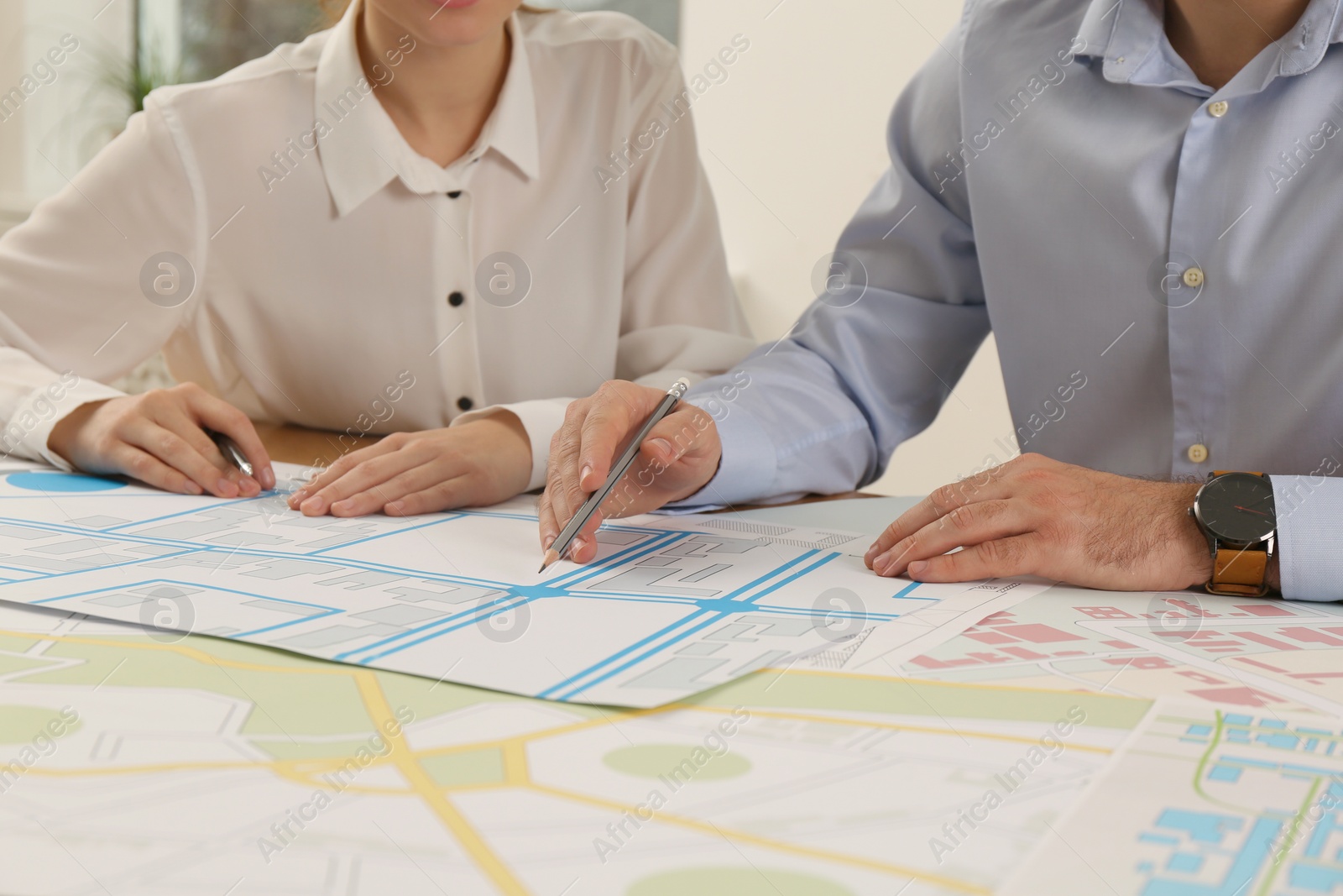 Photo of Professional cartographers working with cadastral map at table in office, closeup