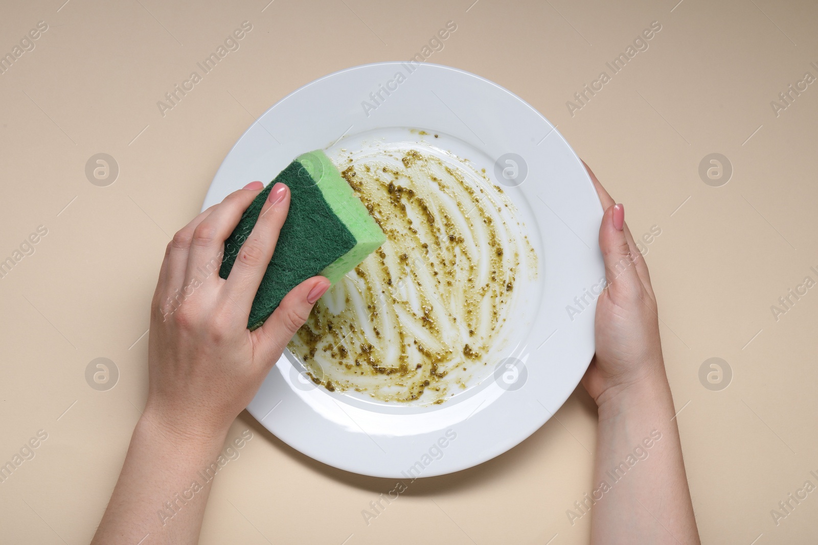 Photo of Woman washing dirty plate with sponge on beige background, top view