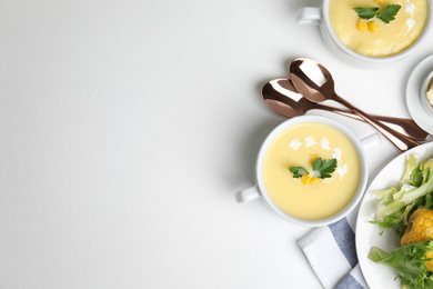 Photo of Delicious corn cream soup served on white table, flat lay. Space for text