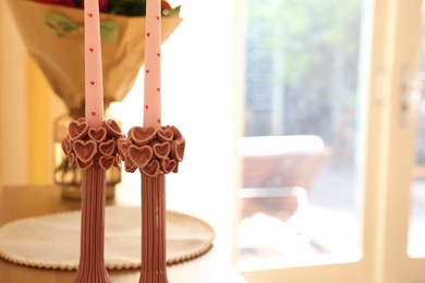 Bouquet of flowers and candles on wooden table indoors. Space for text