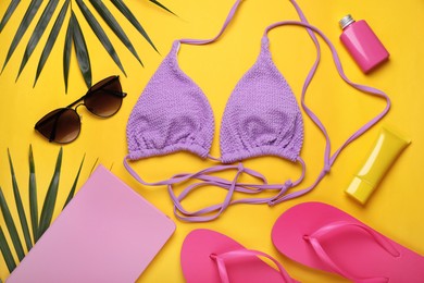 Flat lay composition with sunscreen and beach accessories on yellow background