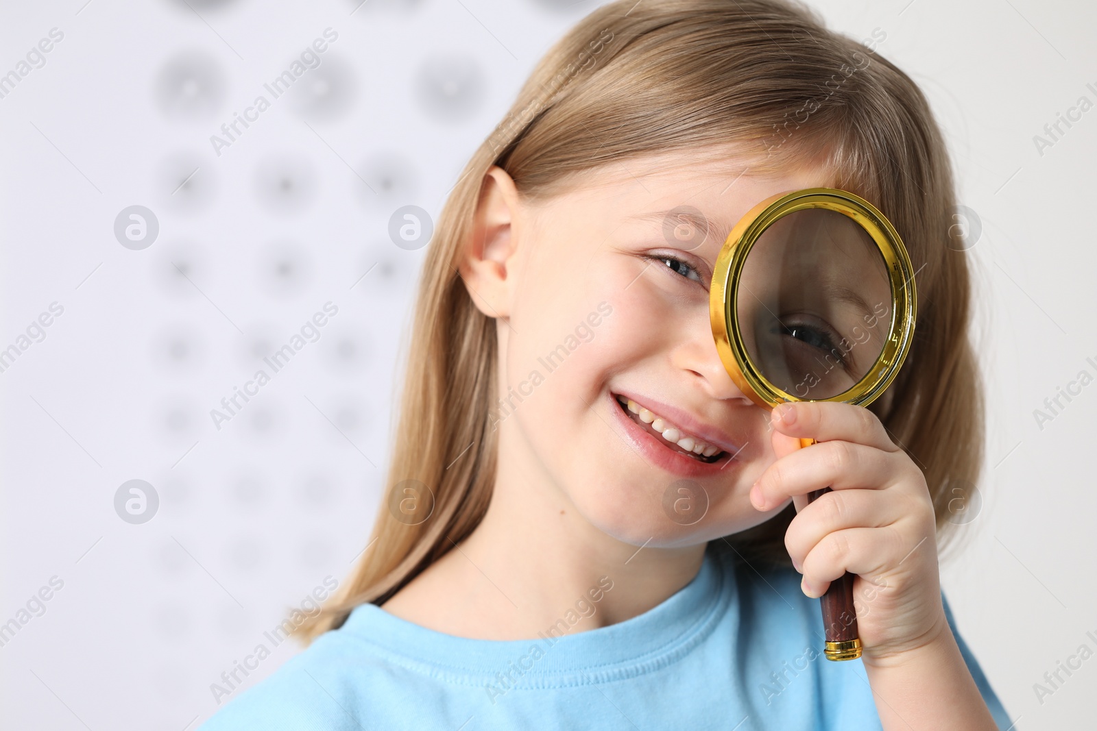 Photo of Little girl with magnifying glass on blurred background