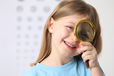 Photo of Little girl with magnifying glass on blurred background